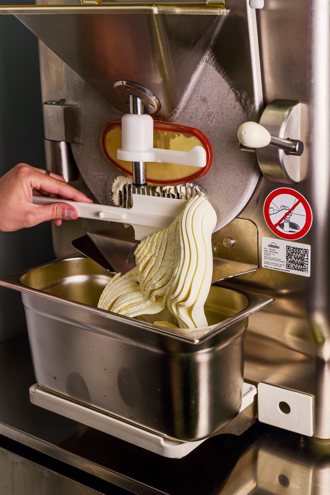 Close-up van de Carpigiani-machine: vers gedraaide gelato loopt in de bak